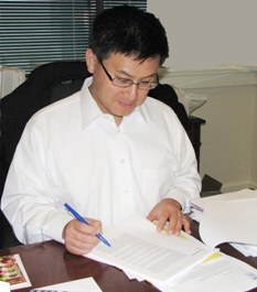 Controller John Chiang reviewing and signing a Controller's audit report