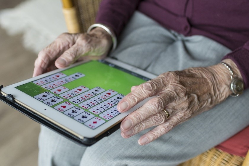 Senior playing digital poker on tablet